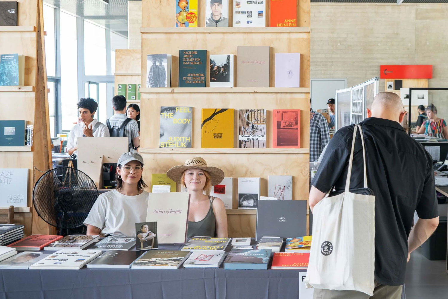 Visitors browsing photobooks at a photobook fair stand